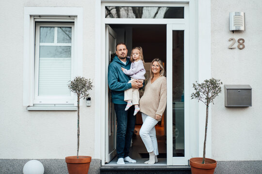 Happy family standing at front door