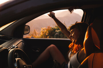 Happy young woman enjoying in car at sunset