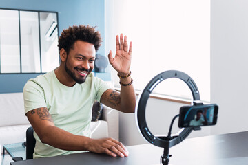 Smiling influencer waving on smart phone at home