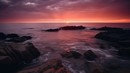 Fototapeta na wymiar A dramatic sunset over the ocean with orange, pink, and purple hues reflecting on the water