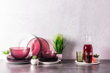 Obraz na płótnie Canvas a set of modern glass burgundy dishes and a jug with grape juice on a stone countertop in the interior of the kitchen. kitchen background.