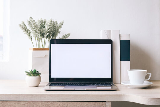 Laptop computer white blank screen on work table at minimalist home office. Cozy room with coffee and books for laptop screen mock up. Front view and mock up. - Powered by Adobe