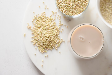 Vegan grain green buckwheat milk in glass on white background. Plant based milk replacer and lactose free. Copy space. View from above.