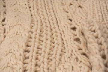 A fragment of beige knitted fabric, knitted from white sheep wool.
