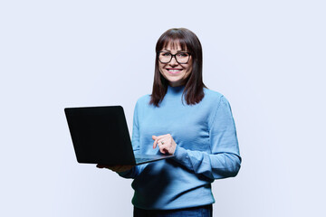 Friendly mature woman using laptop, over white background