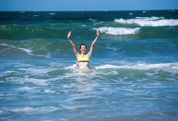 A woman in a swimsuit rejoices and has fun in the sea on the waves