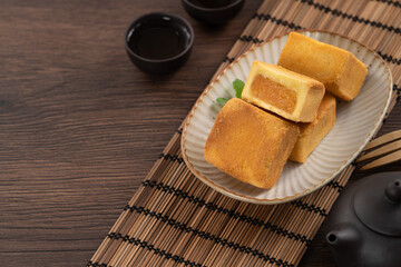 Delicious pineapple cake pastry in a plate on wooden table background with tea.