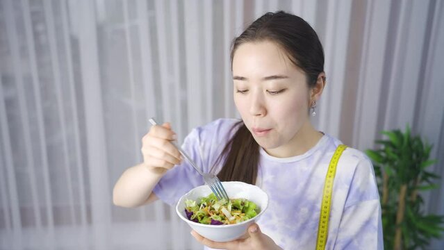 Asian young woman on a healthy diet eats salad.
Healthy diet. The woman consumes vegetables to stay fit and fit.
