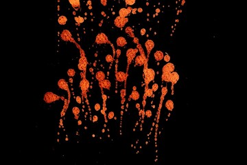 Orange colorful fluorescent splatter on black background,Orange color abstract,Abstract Textures 	