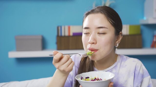 Asian Young woman is on a vegetarian diet. Health and diet plan. 
Healthy eating Asian woman makes vegetarian diet. Eating salad.

