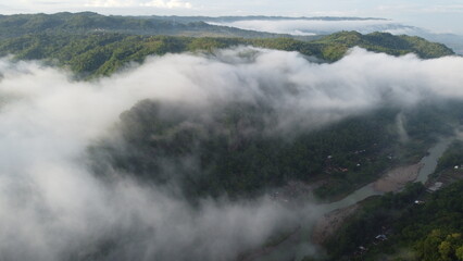 Obraz premium Amazing aerial view of beautiful low clouds creeping on the tree-covered mountain slopes