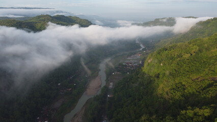 Amazing aerial view of beautiful low clouds creeping on the tree-covered mountain slopes