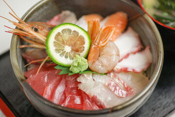 新鮮な鮪や鯛、大きな海老などの厳選素材を贅沢に盛り込み、瑞々しい輝きを放つ「海鮮丼」。しっとり柔らかな身の質感が際立つ一景で、和食店のランチや旅先の御膳、贅沢な海鮮メニューの販促に最適な高品質素材です。 | Fresh seafood bowl with tuna, sea bream, and a whole prawn.