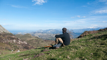 Naklejka na ściany i meble Hombre joven barbudo sentado en ladera de montaña de Asturias