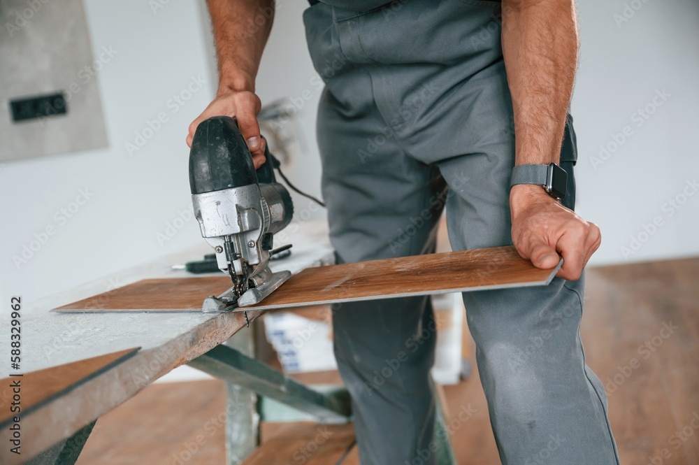 Wall mural Cutting the planks. Man is installing new laminated wooden floor