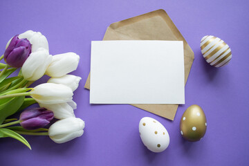 Easter greetings: paper letter copy space on a purple background. Bouquet of white tulips and easter eggs golden and with pattern