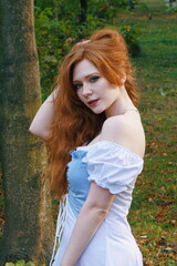 Portrait of a red-haired girl with freckles in the forest