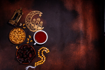 Ramadan muslim holiday background, with traditional treats - dates, nuts, dried fruits, sweets, religion rosary beads, lantern, tea, islamic Mosque, crescent moon Ramadan Kareem themed decorations