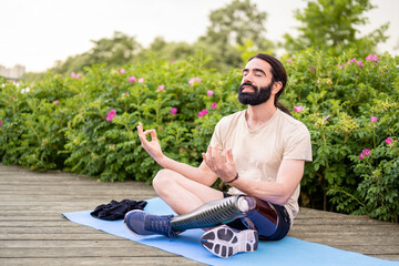 Young man of Hispanic origins with a disability practicing yoga  at city park, concept of...