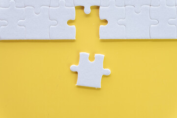 Obraz premium Top view photo of a White jigsaw or puzzle last piece to complete on yellow background with copyspace suitable for lat lay top view mock-up item,business and design,abstract concept.