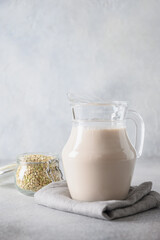 Green buckwheat milk in glass jug on gray background. Alternative plant based milk replacer. Vertical format.