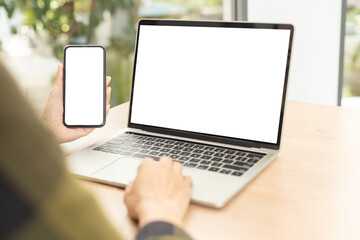 Fototapeta premium computer screen,cell phone blank mockup.hand woman work using laptop texting mobile.white background for advertising,contact business search information on desk in cafe.marketing,design