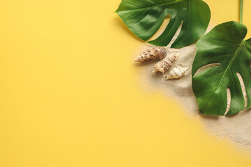 Fototapeta na wymiar monstera leaves, sand, seashells on a yellow summer background, space for text