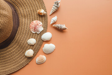 Beautiful straw hat and seashells on color background, top view