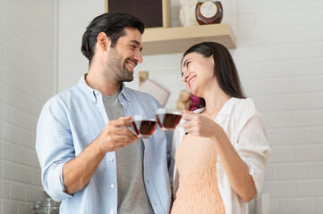 Happy couple drinking coffee at kitchen counter in the morning at home
