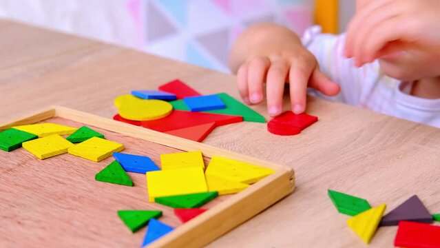 Happy 3 years toddler, child having fun with building and creating wooden geometric figures at home, in kindergarten, creating patterns, concept of fine motor skills, learning mathematics and geometry