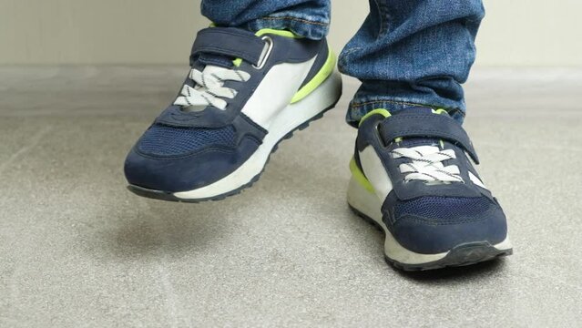 An impatient disgruntled preschool or school child stomps his feet, close-up