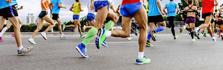 close-up legs runners, men and women, running marathon. athletes jogging city race, summer world...