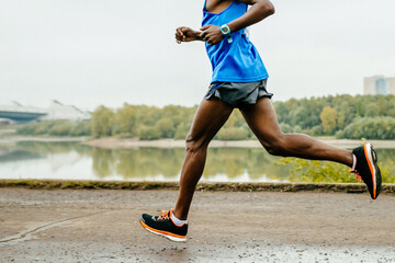 male african runner athlete running marathon race in embankment river, legs jogger run world...
