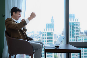 Young businessman sit and relax in the relaxation room by the window overlooking the beautiful city buildings. happy to receive good news