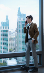 Young businessman sit and relax in the relaxation room by the window overlooking the beautiful city buildings. along with the phone to talk about business.