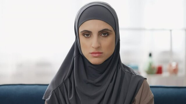Portrait of unhappy Muslim woman in hijab at home, women's rights discrimination