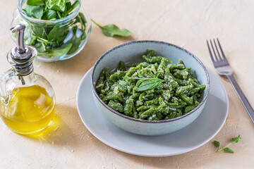 Spinach spatzle (or green spatzle) are the typical Tyrolean green dumplings or gnocchi on plate with fresh spinaches, olive oil