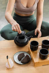 cropped view of woman in sportswear brewing puer tea in Chinese teapot.