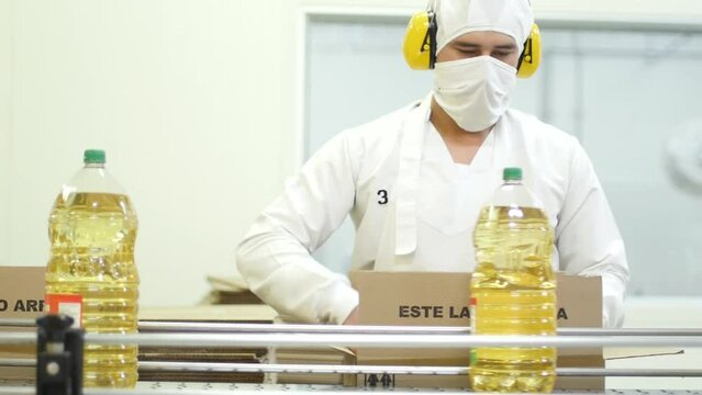 Male factory worker boxing sunflower oil in the product line-HD