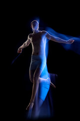 Obraz premium Portrait of young guy wearing underwear jumping in motion over dark background. Futuristic man from future. Mixed neon light