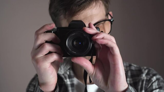 Young hipster man taking pictures with a retro camera. slide. studio