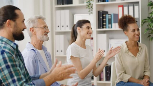 Diverse people applauding and supporting person at therapy session, recovery