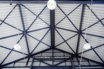 Roof of industrial hangar or warehouse with metal ceiling and lighting lamps. Inside view..
