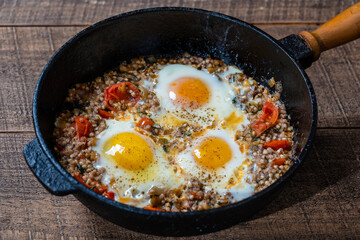 Boiled buckwheat with fried eggs, red peppers, tomato and onions, closeup, Ukraine. Food background. Healthy food