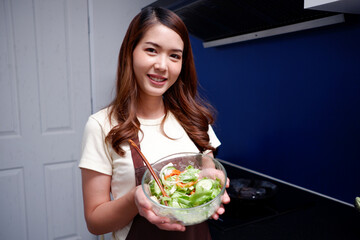 Smiling woman holding a plate of vegetable salad healthy food concept.