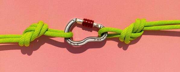 carabiner with a rope lies on a colored background. Equipment for climbing and mountaineering....