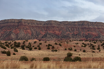 Stunning brush covered red rock cliff face with tall grass and overcast sky in the high desert