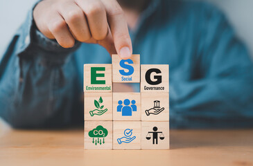 Businessman assemble ESG wording on wooden cube block for sustainable organization development and corporation of Environment Social Governance concept.