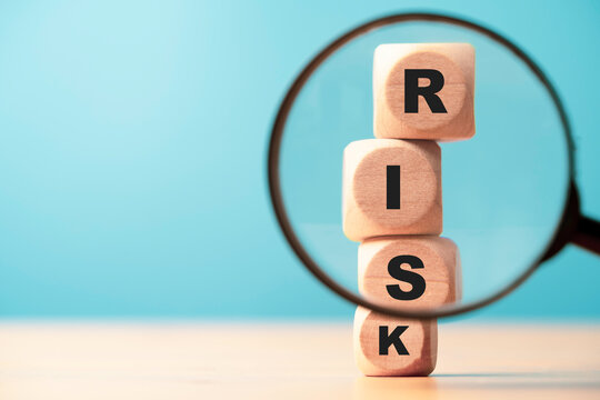 Risk wording print screen on wooden block cube and focus on magnifier glass for financial banking risk analysis and management ,Risk and return concept.
