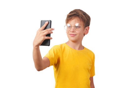 Young teenager in glasses and a yellow t-shirt taking a selfie. Half-length studio portrait, isolated on a white background